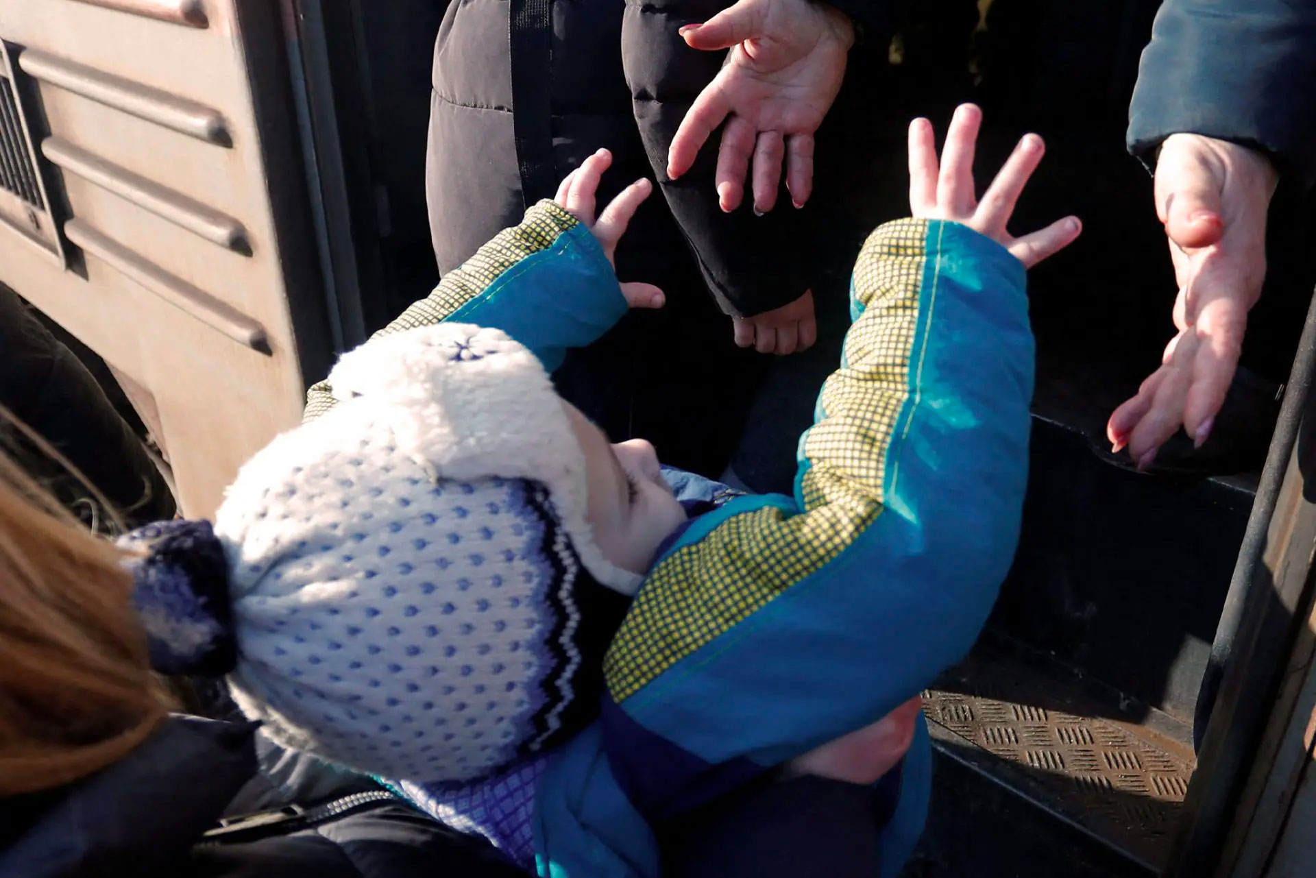 Ett litet barn blir upplyft i en bil av en vuxen person. Fotot är taget av Reuters och tillhandahållet av UNHCR.